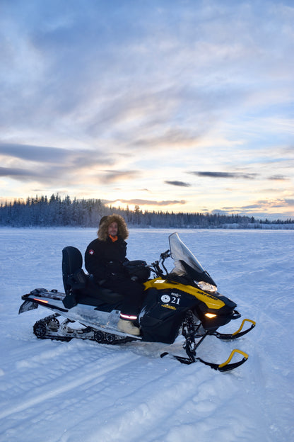 Person sitting on a snowmobile in a snowy landscape with a sunset sky in Fairbanks Alaska 
