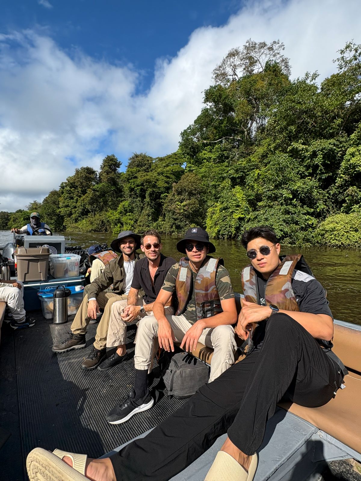 Group of people on a boat in a forested area with trees and water in the background  on the amazon river exploring