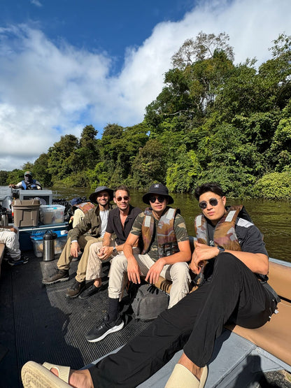 Group of people on a boat in a forested area with trees and water in the background  on the amazon river exploring
