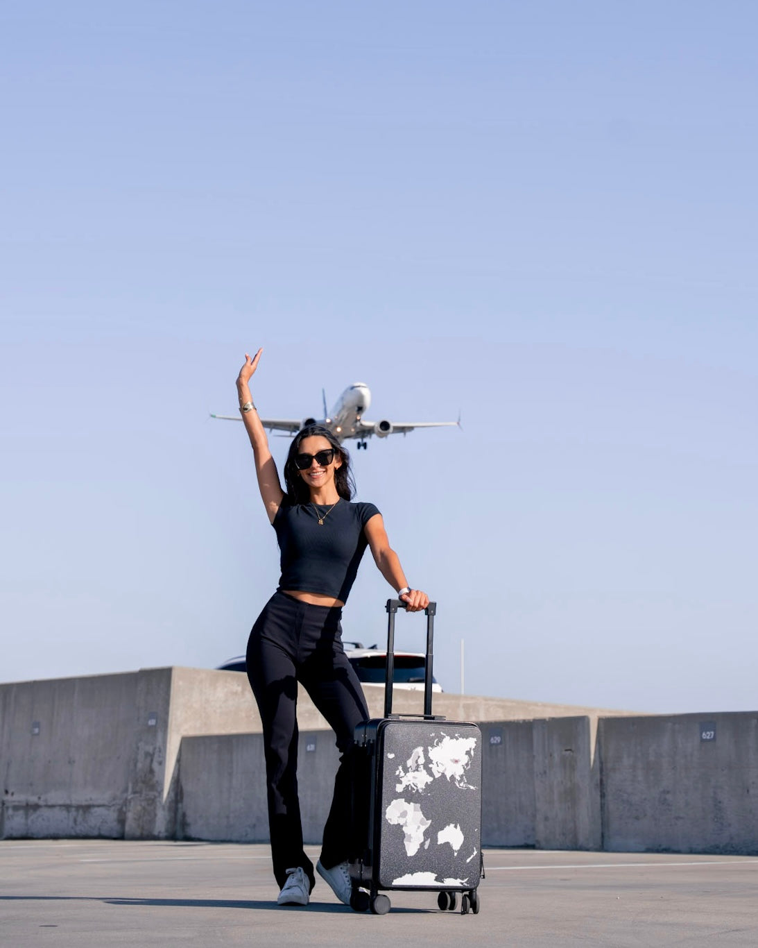 Person with a suitcase and airplane in an open area with a clear sky