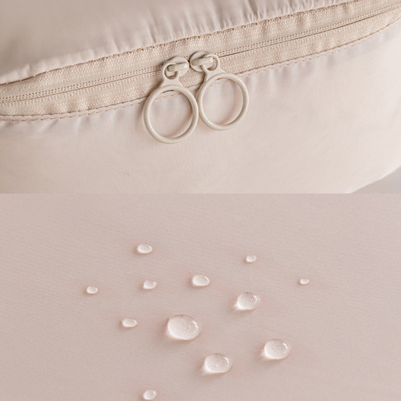Close-up of a beige fabric with water droplets and a zipper, on a light pink background.