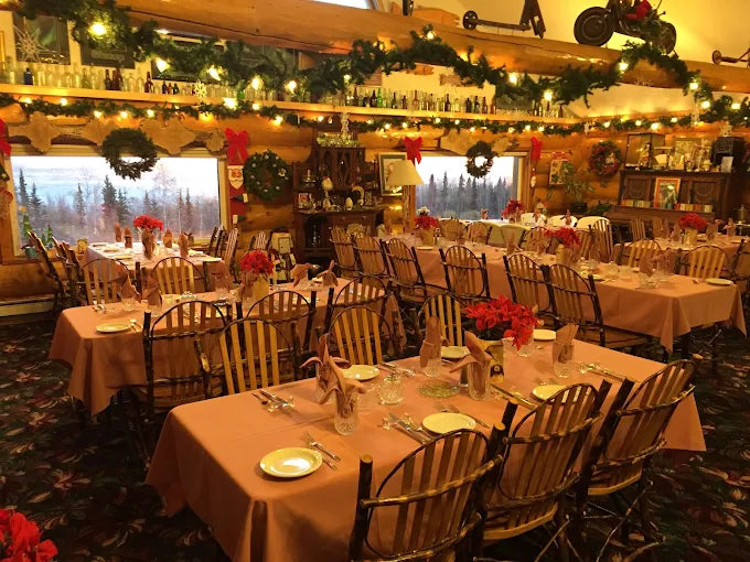 Decorated dining room with tables set for a meal, Christmas decorations, and a scenic window view.