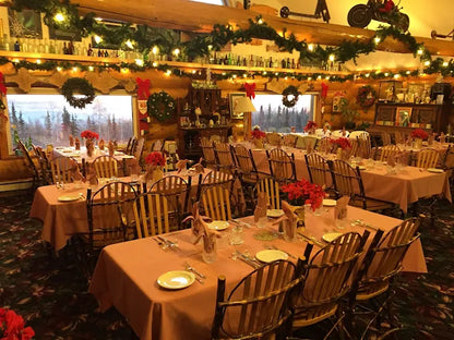 Decorated dining room with tables set for a meal, Christmas decorations, and a scenic window view.