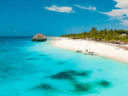 Tropical beach with clear blue water and a resort in the background in zanzibar
